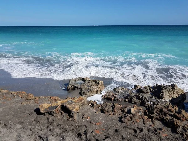 Rocas y arena en la costa en la playa de Florida con el océano y las olas —  Fotos de Stock