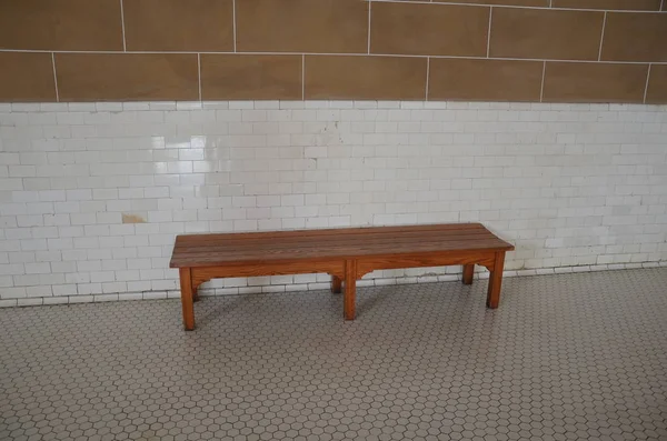 Brown wood bench with hexagon floor tiles and white wall tiles — Stock Photo, Image