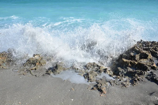 Mavi okyanus suyu sahildeki kayalara sıçrıyor. — Stok fotoğraf