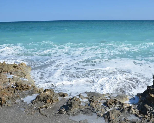 Agua azul del océano salpicando en las rocas en la playa —  Fotos de Stock