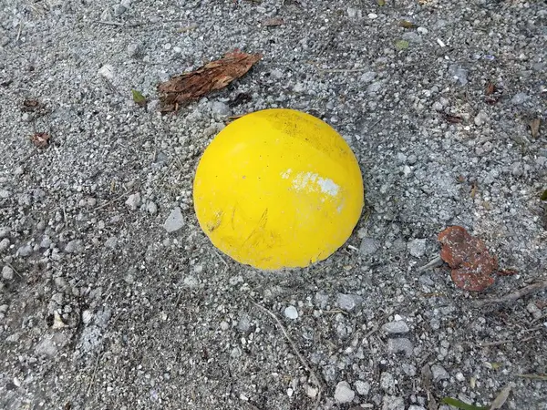 Sfera di cemento giallo a terra con ciottoli — Foto Stock