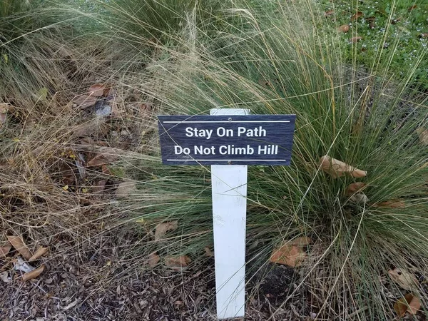 Stay on path do not climb hill sign with grasses — 스톡 사진