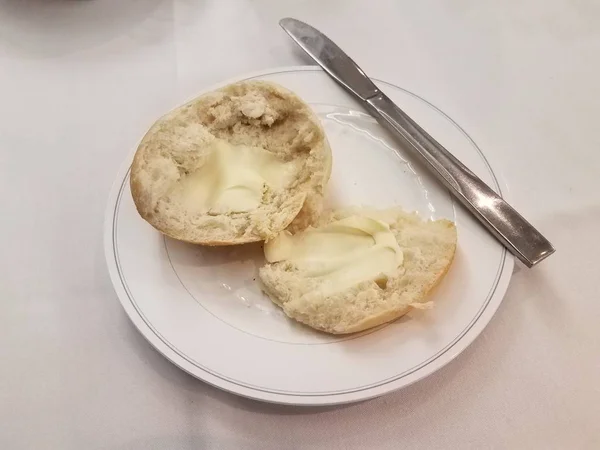 Brød roll på hvid plade med smør og kniv - Stock-foto