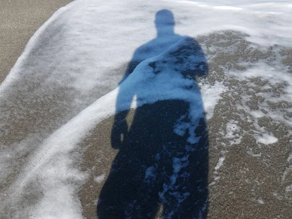 젖은 모래 위에 물을 가진 인간의 그림자 — 스톡 사진