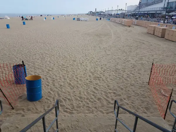 Ocean water at coast or shore with stairs and sand and buildings — Stock fotografie