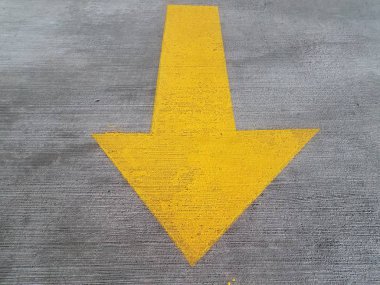 yellow arrow painted on grey cement on ground