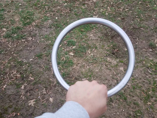 Hand holding metal circle over grass or lawn — 스톡 사진