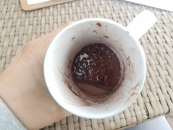 Hand holding white cup with melted chocolate and brown table — Φωτογραφία Αρχείου