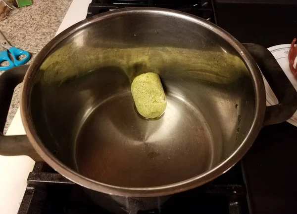 Frozen green pesto sauce in a metal pan on stove — стоковое фото