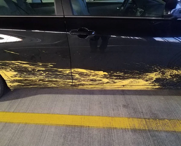Black car with yellow paint splatter and cement with line — стоковое фото