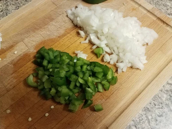 Onion and green pepper on wood cutting board — Stock Photo, Image