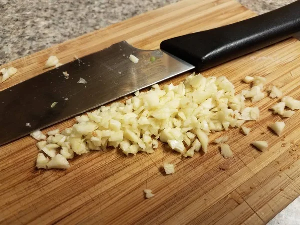 Alho picado em uma tábua de corte com faca — Fotografia de Stock