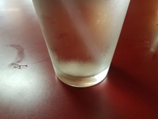 Glass of water with condensaton and straw on red table — 图库照片