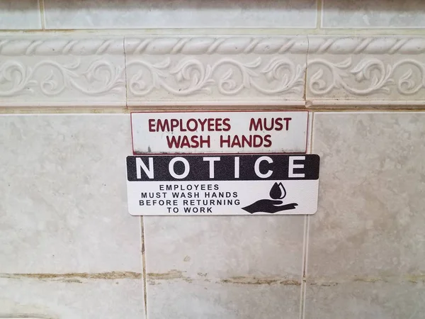 Notice employess must wash hands sign on bathroom wall — 图库照片