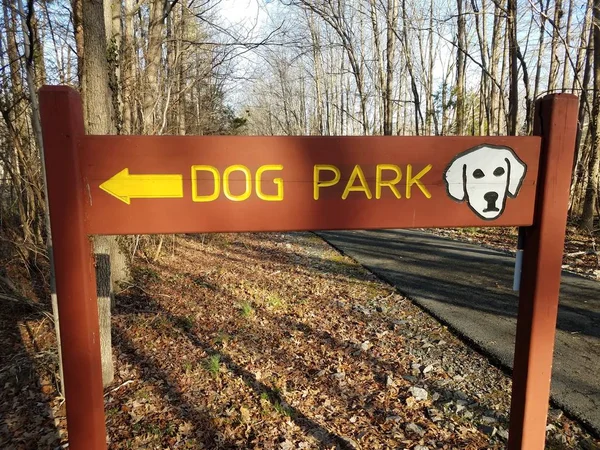 木狗公园标志，黄色箭头，柏油路和树木 — 图库照片