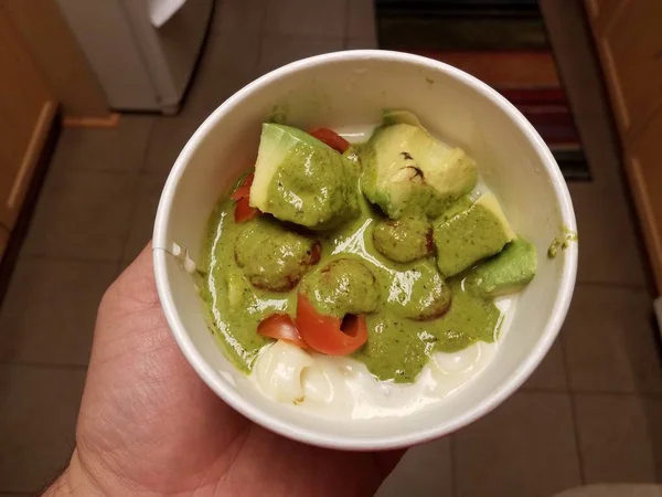 Hand houden kom van cheesy pasta met avocado — Stockfoto