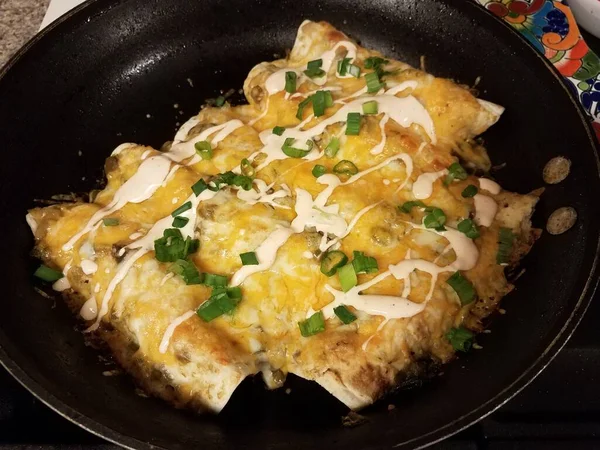 Enchiladas in frying pan with sauce and onions — Stockfoto
