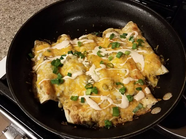 Enchiladas in frying pan with sauce and onions — Stock fotografie