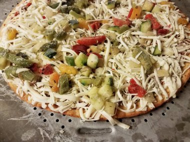 Metal pişirme tepsisinde peynirli donmuş sebze pizzası.