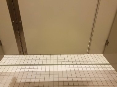 grey bathroom stall door with white tiles