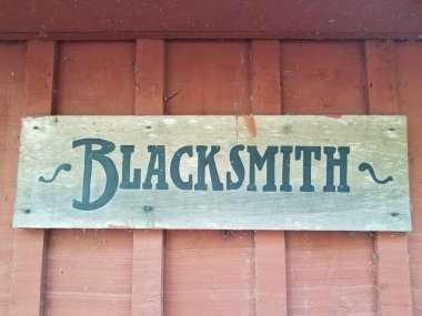 wood blacksmith sign on dirty red wall