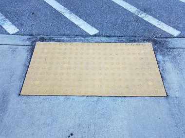 yellow tactile bumps on cement sidewalk or ground
