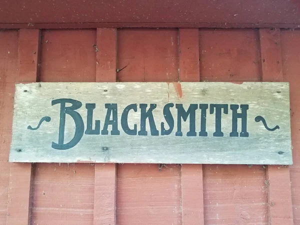 Wood blacksmith sign on dirty red wall — ストック写真