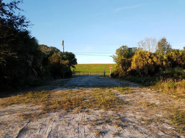 Camino de tierra con señal de stop y puerta y árboles —  Fotos de Stock