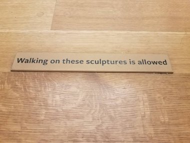 walking on these sculptures is allowed sign on wood floor