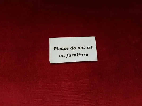 Просим не сидеть на табличке на красной дорожке — стоковое фото