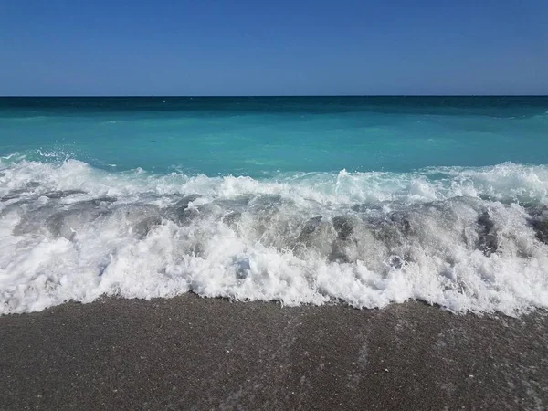 White waves crashing on sand with ocean — Stockfoto