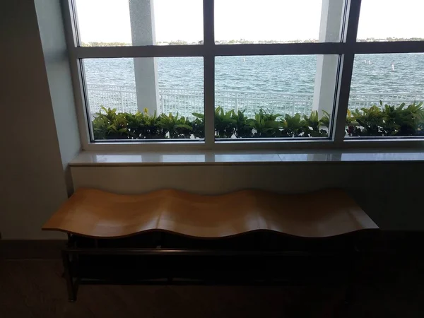 wavy wood bench with window and sea water