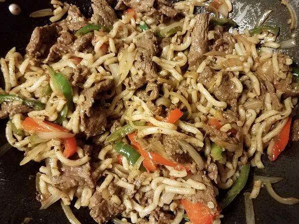 Noodles and beef and peppers in frying pan — 스톡 사진