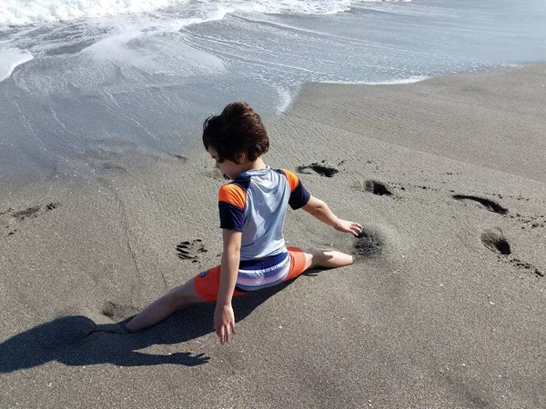 Niño haciendo las divisiones en la arena en la playa —  Fotos de Stock