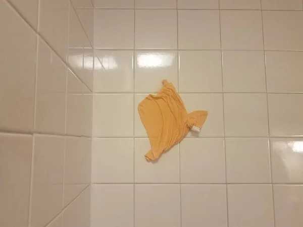 Orange cloth or rag stuck on bathroom tiles — Stockfoto