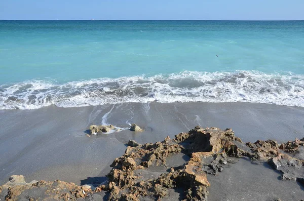 Sand and rocks and ocean water at beach — Stockfoto