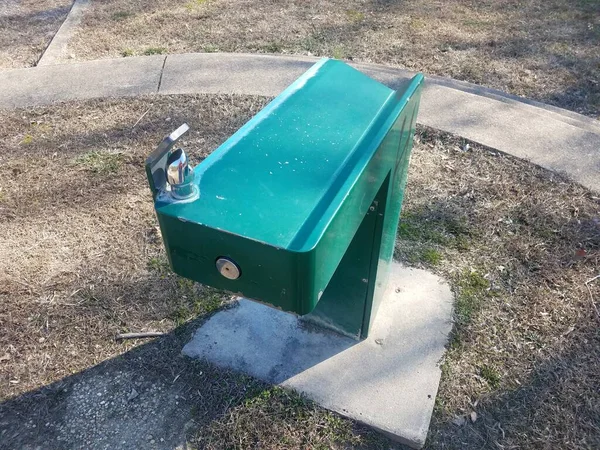 Green water fountain in park with grass — ストック写真