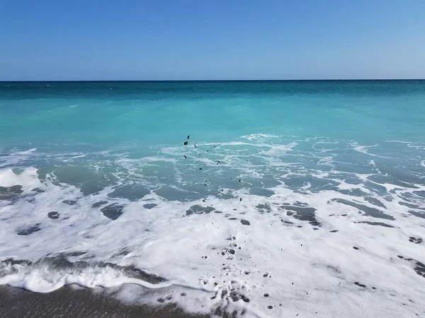 Arena lanzada al aire en la playa con olas del océano — Foto de Stock
