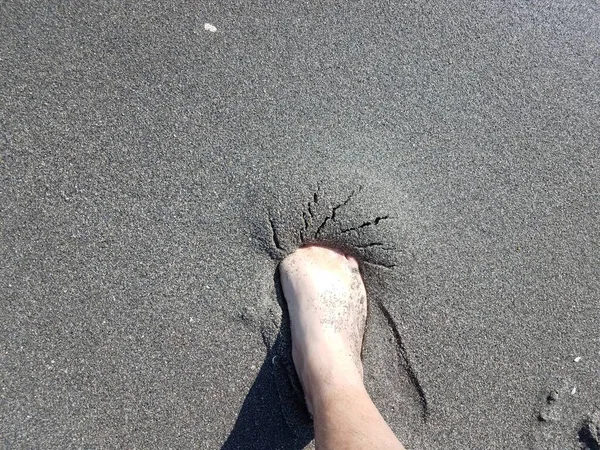 Männlicher Fuß im grauen, nassen Sand am Strand — Stockfoto