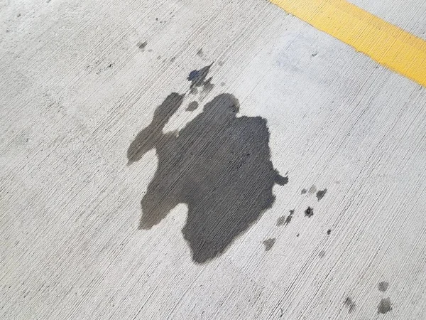 Oil stain or puddle on grey cement in parking space — Stok fotoğraf