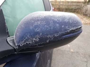 frost on blue car mirror in asphalt driveway