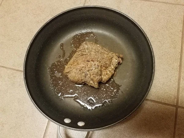 Raw beef meat in frying pan on tile floor — Stock fotografie