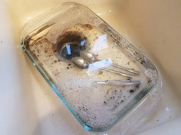 Bandeja de vidrio sucio con agua en fregadero con utensilios de plata —  Fotos de Stock