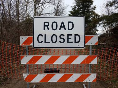 white road closed sign and striped barricade with trail or path