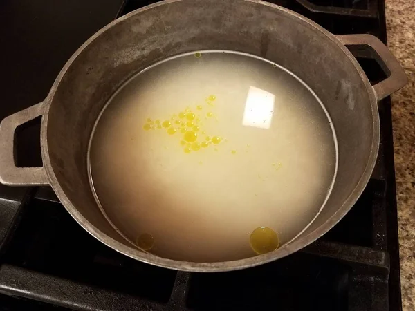 Oil and murky water in metal pot on stove — 스톡 사진