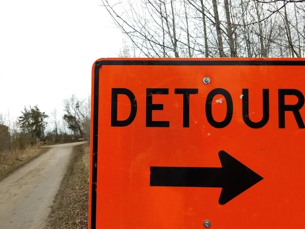 Orange detour sign with black arrow with trail or path — Stockfoto