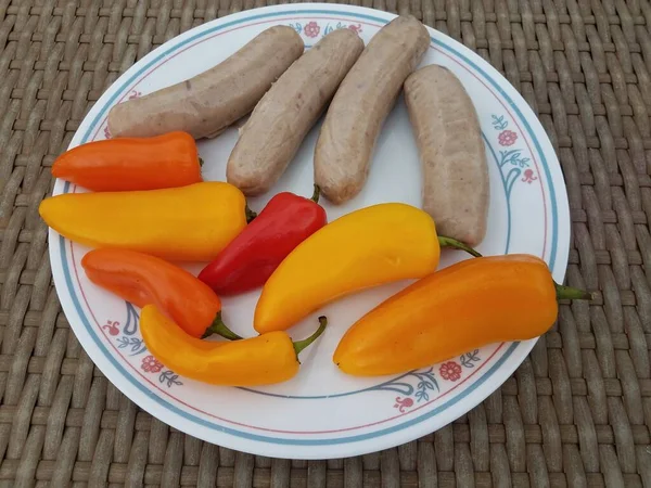 Sausages and colorful peppers on white plate — Stock fotografie