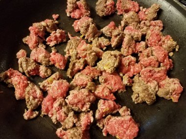 raw and cooked ground beef in frying pan