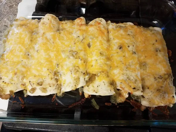 Enchilada panggang dengan keju di nampan kaca di atas kompor — Stok Foto