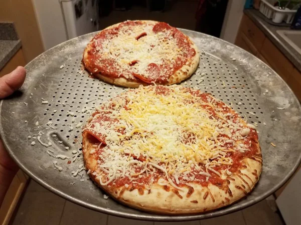 Рука держит металлический поднос для выпечки с пиццей — стоковое фото